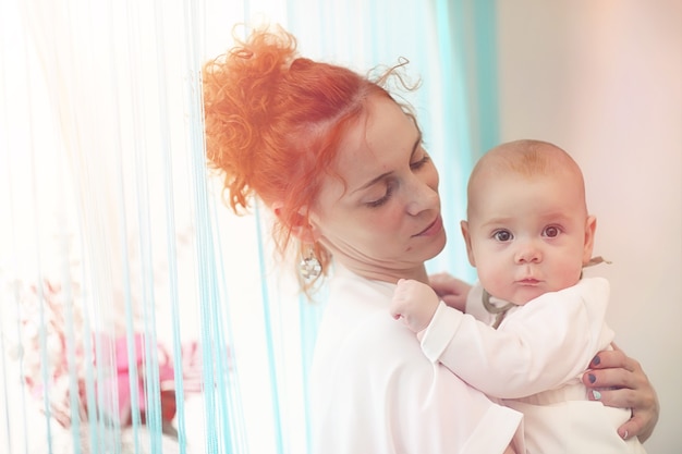 Baby in the arms of the girl. Mom holds her child in her arms. Happy mother with a little baby