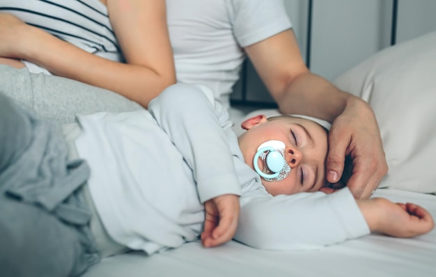 Baby asleep while his parents caress him