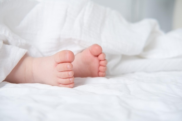 Photo baby bare feet on a white bed with a white blanket