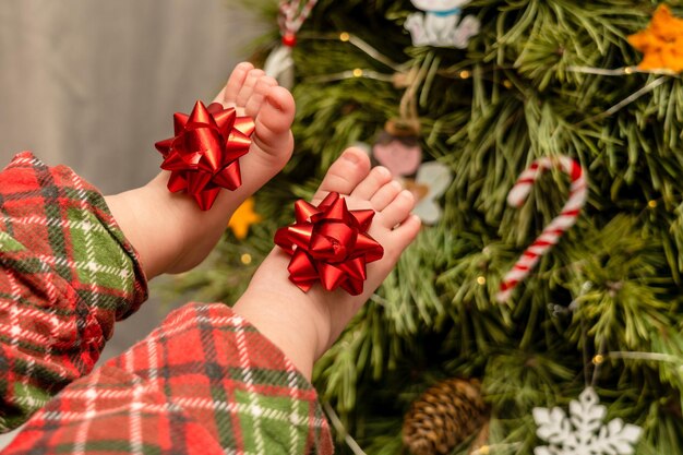 Baby bare feets with a bow near the Christmas tree