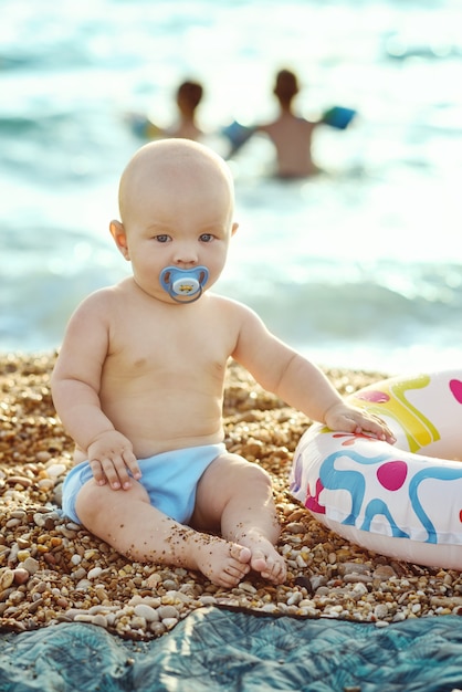 Baby on the beach sitting on the pebble