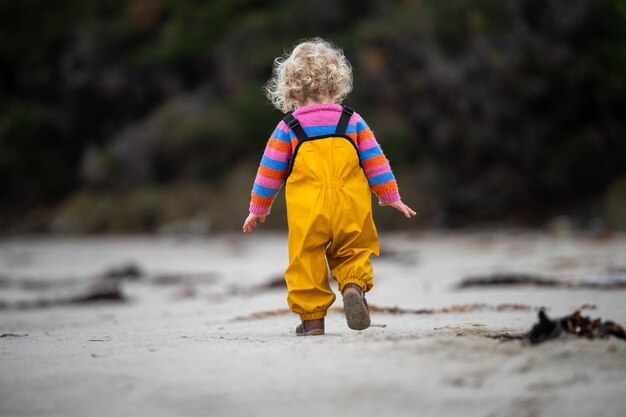 baby on the beach in yellow overalls in spring