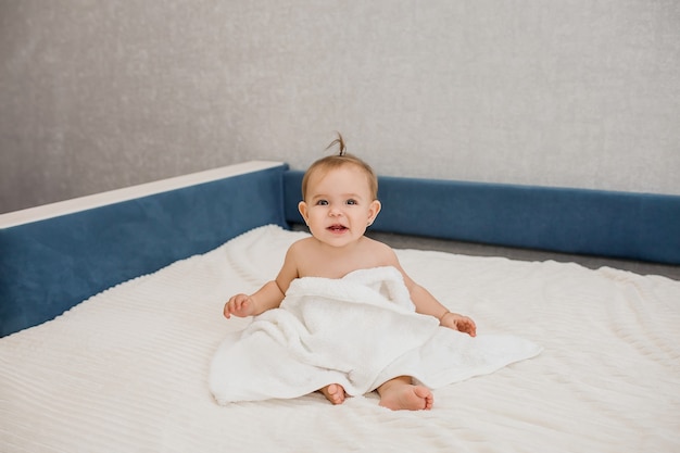 baby beautiful little girl sitting on the couch in a towel