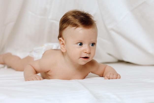 Baby in bed Adorable toddler lying on stomach against white background