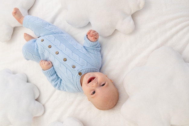 Baby on the bed among the cloud pillows. Textiles and bedding for children.