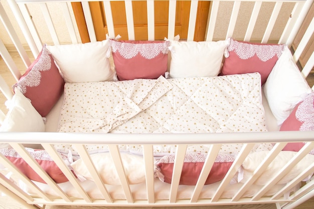 Photo baby bed crib with white and burgundy color pillows with laces