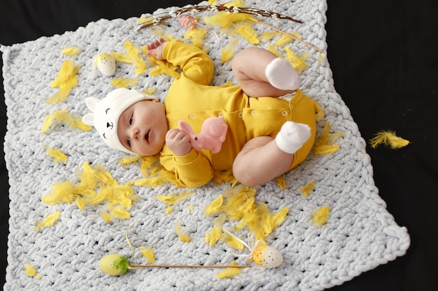 Baby on the bedspread. Baby in yellow clothes.