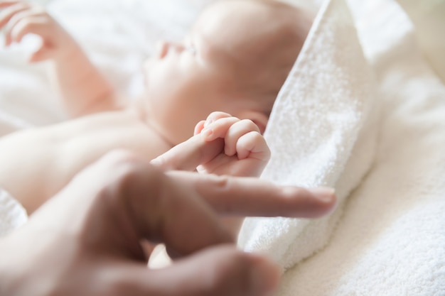 Младенец в одеяле, держащий за палец своего родителя