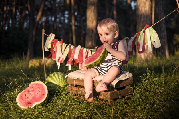 Baby blonde jongen eet watermeloen en glimlach.