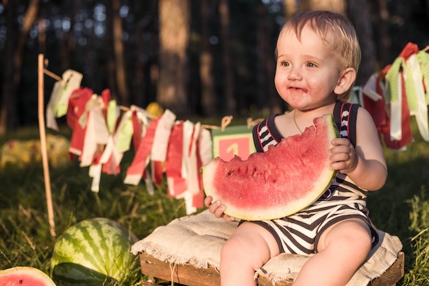 Baby blonde jongen eet watermeloen en glimlach.