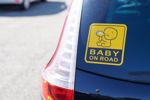 Baby on board warning sign text on rear windows car in street