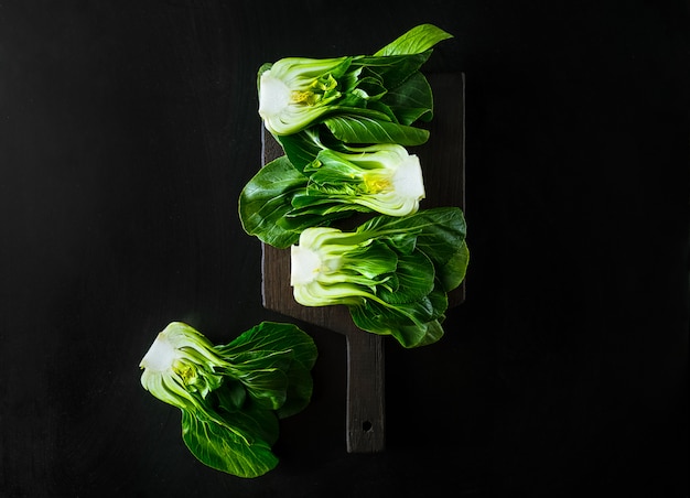 Baby bok choi halves on black background