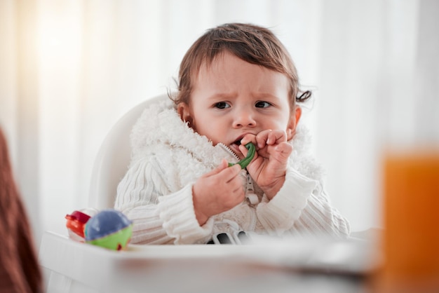 Baby boos kind en groenten eten in huis voor gezondheid, welzijn en voeding Boos kind kinderstoel en voedselgroenten of ontbijt in de keuken voor gezonde voeding, groei en ontwikkeling in huis