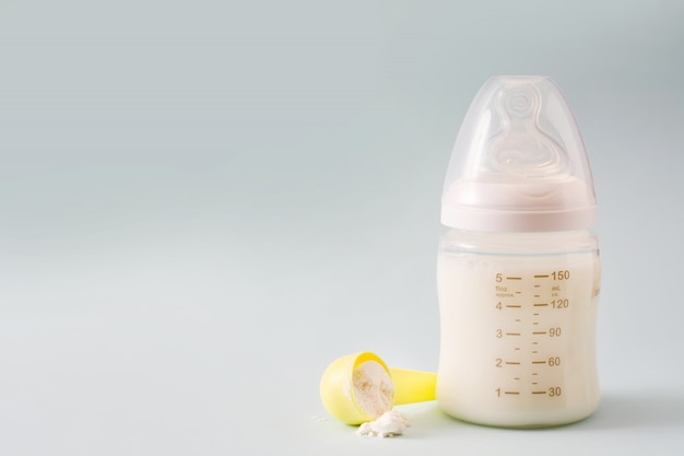 Photo baby bottle and milk on gray copy space