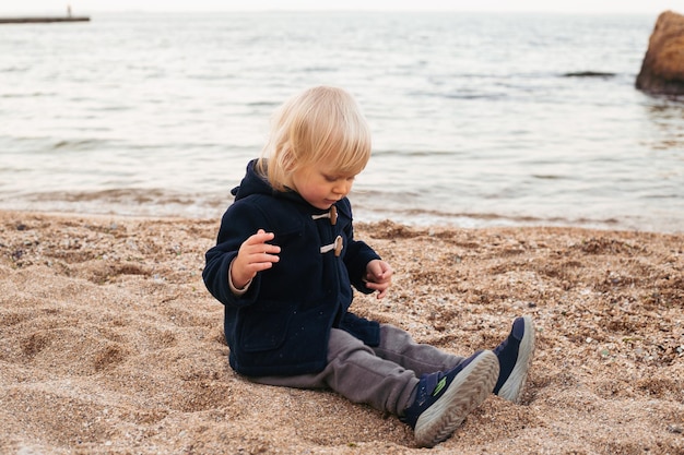 海の近くのビーチで男の子 夏または秋に休暇中の子供 秋または夏の悪天候で海で