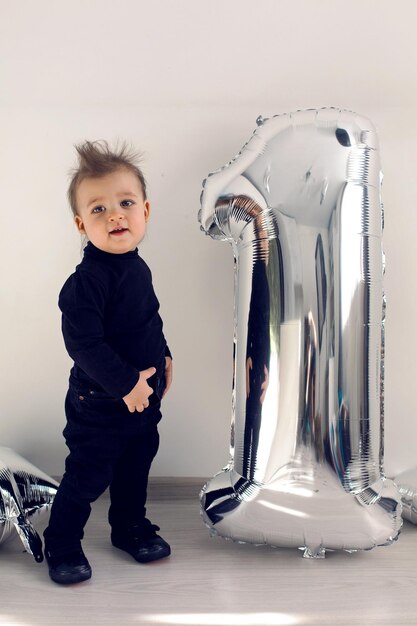 Photo baby boy in black clothes one year with silver inflatable figure