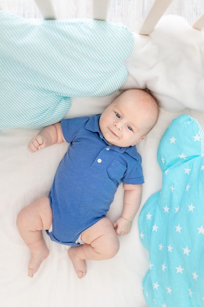 Мальчик в кроватке среди подушек концепция детского белья и текстиля