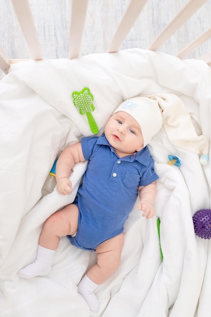 Baby boy in a crib among baby supplies baby products concept