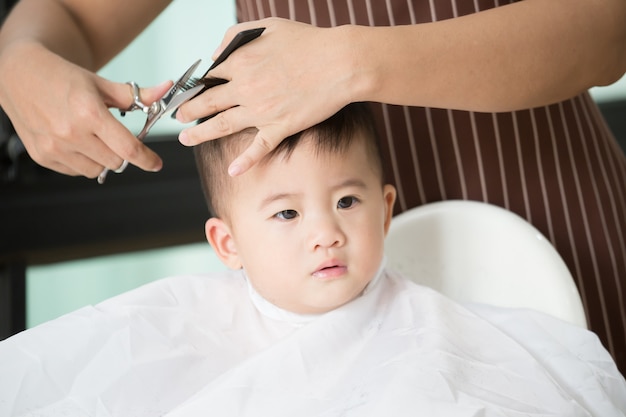 Baby boy cutting hair by his mom at home