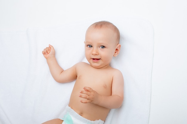 A baby boy in a diaper is lying on a white background isolated