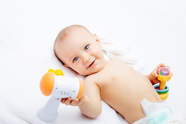 A baby boy in a diaper with toys lies on a white background isolated