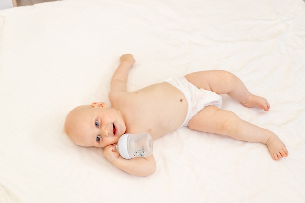 Baby boy in diapers on a white bed