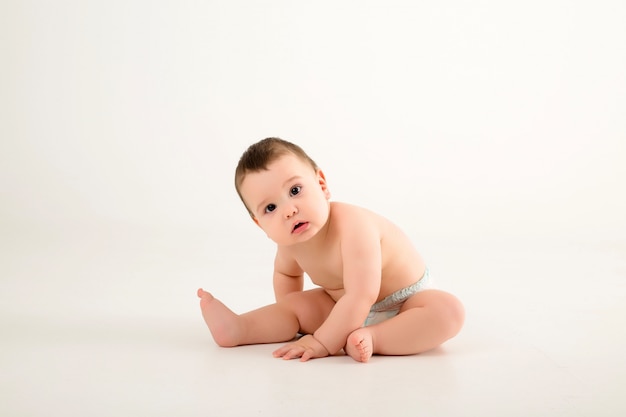 baby boy in diapers on white wall