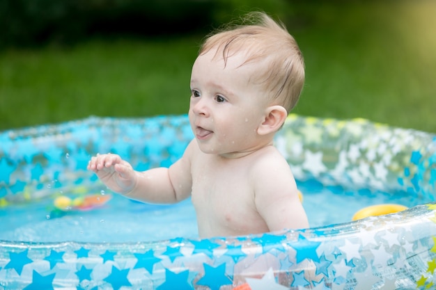 Baby boy having fun in swimming pool at garden