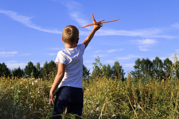 Un bambino sta lanciando un aliante giocattolo in un campo