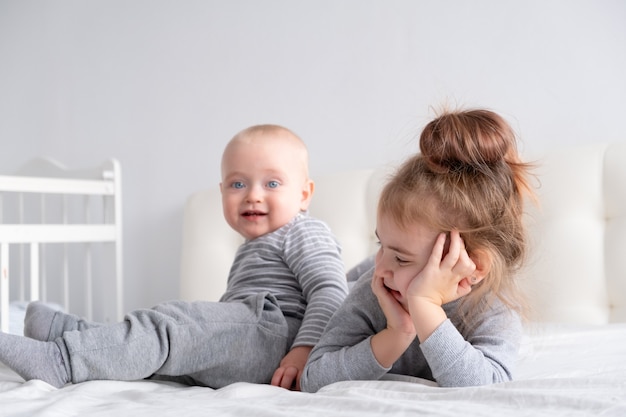 Baby boy and little girl sister having fun at home on bed. Home activities for kids.