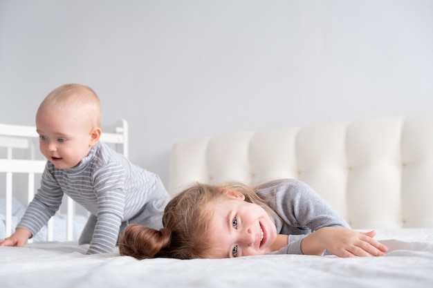 Baby boy and little girl sister having fun at home on bed. Home activities for kids.