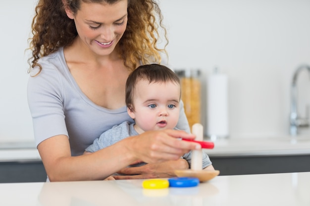 Baby boy looking at mother playing with toys