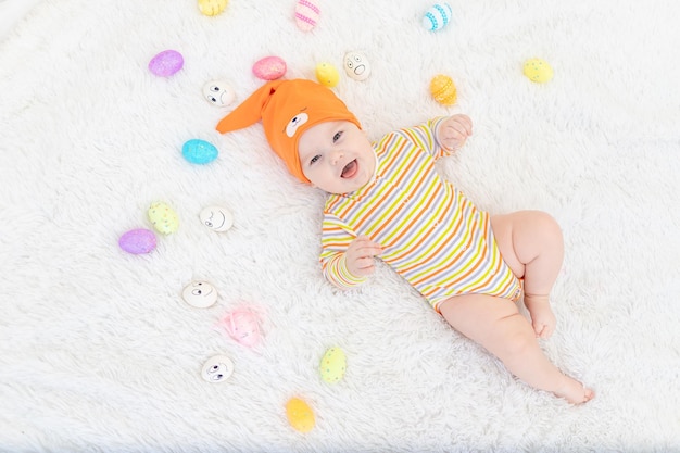 Baby boy in orange clothes lying with Easter eggs cute funny smiling little baby The concept of Easter