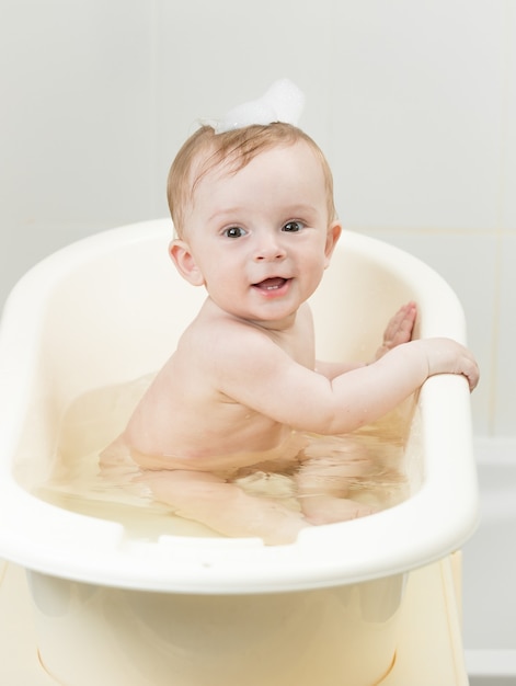 Baby boy playing in foam while having bath