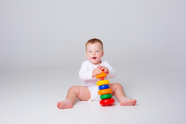 Baby boy playing a multicolored pyramid on a white background