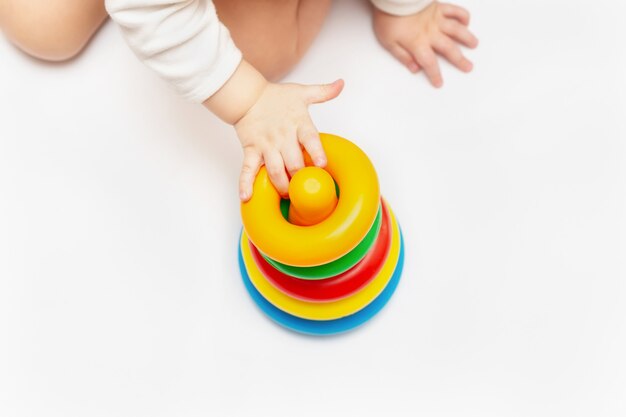 Baby boy playing with colorful rainbow toy pyramid. Toys for little kids. Child with educational toy. Infant early development