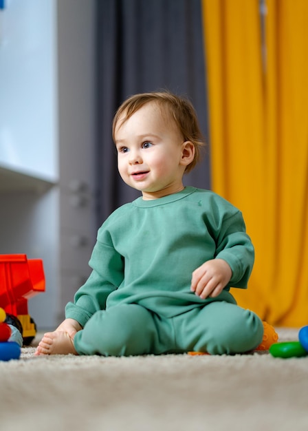 아기 소년 교육 장난감을 가지고 노는 귀여운 어린 소년이 바닥에 앉아 장난감을 가지고 놀고 있다