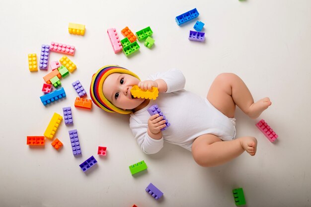 Photo baby boy playing with a multi-colored constructor on a white wall