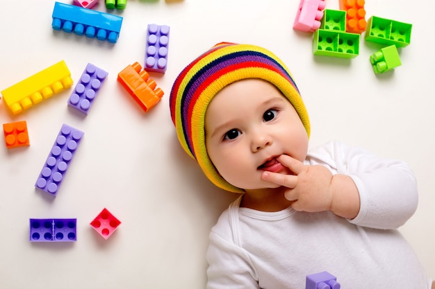 baby boy playing with a multi-colored constructor on a white wall