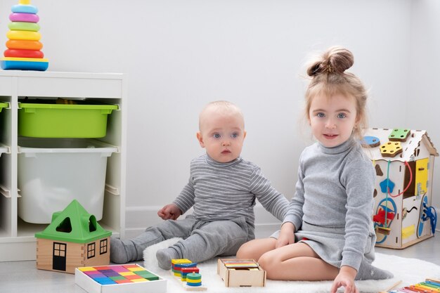 Baby boy playing with older sister with wooden toys. early children development.