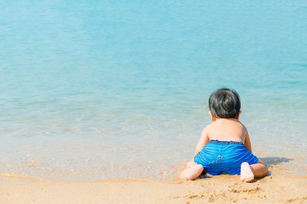 Neonato che gioca con la sabbia sulla spiaggia