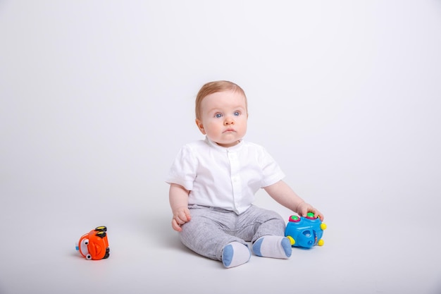 Baby boy playing with toy cars on white background