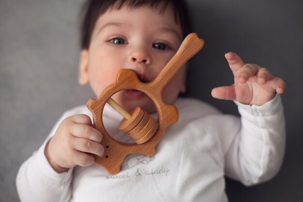 Baby boy playing with wooden toy on grey