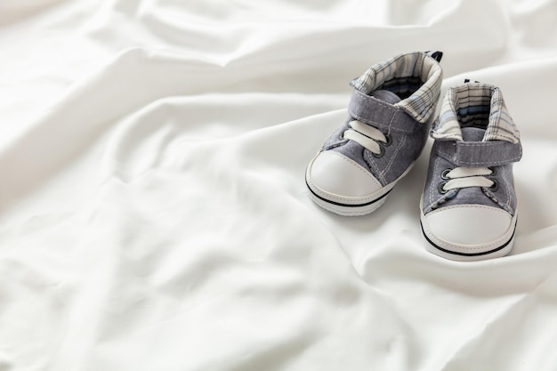 Baby boy shoes on white satin copy space