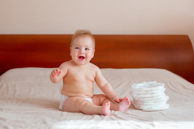 Baby boy sits in a diaper on the bed in the bedroom