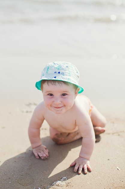 Baby boy sitting on beach sea