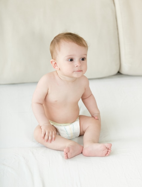 Photo baby boy sitting on bed at bedroom