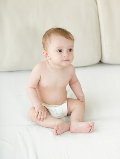 Baby boy sitting on bed at bedroom