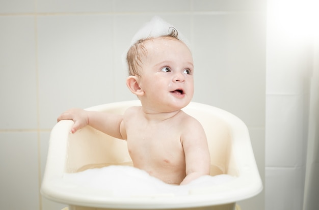 Baby boy sitting in foam at bathroom