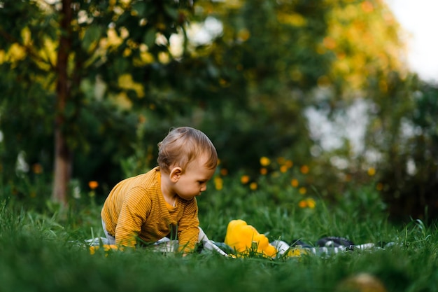 夏の日に草の上に座っている男の子トレンディでかわいい服を着た子供